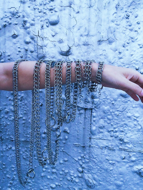 chainmail necklaces and chokers dangling off of an arm