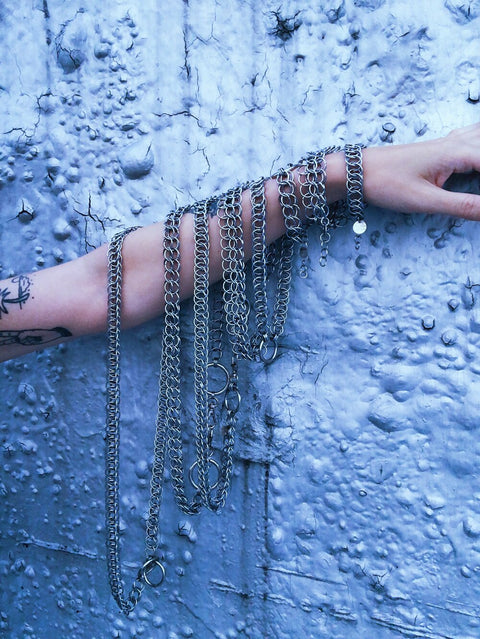 stainless steel chainmail chokers and bracelets dangling on an arm