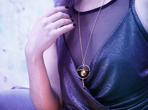 Dangly Saturn pendant featuring intersecting rings and a dangly moon charm