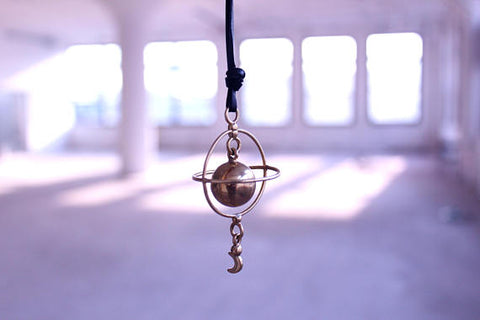 Dangly Saturn pendant featuring intersecting rings and a dangly moon charm